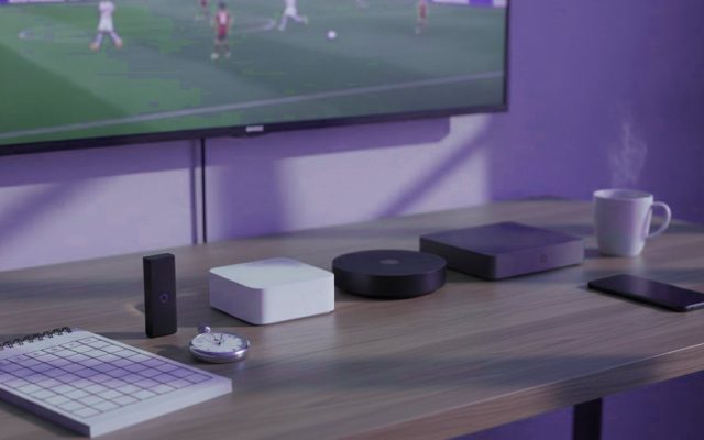 Five streaming devices, a notebook scoring grid and a stopwatch in front of a TV showing a football match